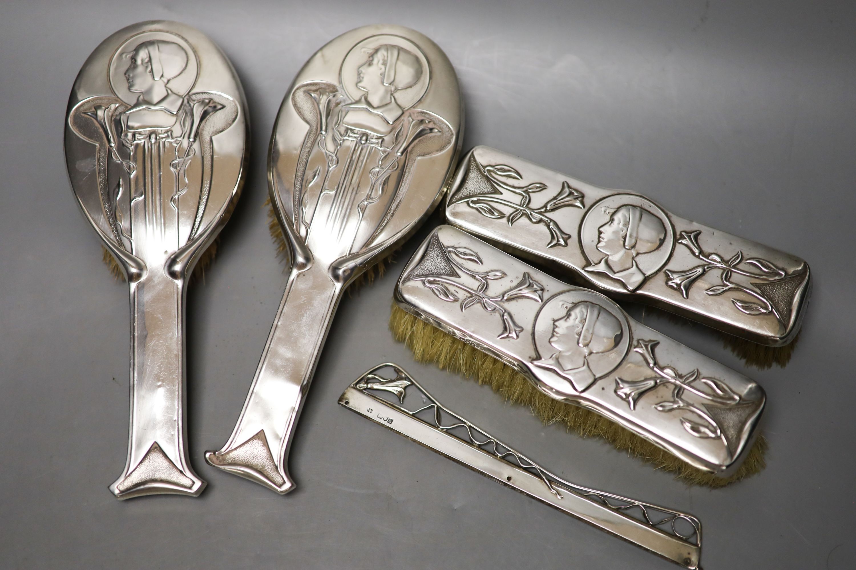 An Edwardian Art Nouveau silver mounted brush and comb set (a.f.), by William Hutton & Sons, London, 1904(4) and Birmingham, 1907(1), largest 24.6cm